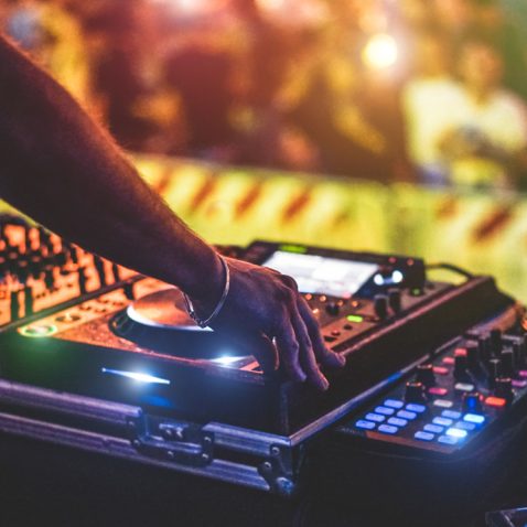 Dj mixing outdoor at new year party festival with crowd of people in background - Nightlife view of disco club outside - Soft focus on bracelet, hand - Fun ,youth,entertainment and fest concept